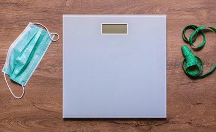 Image: Adobe A weighing scale on a wooden floor next to a tape measure and a surgical face mask