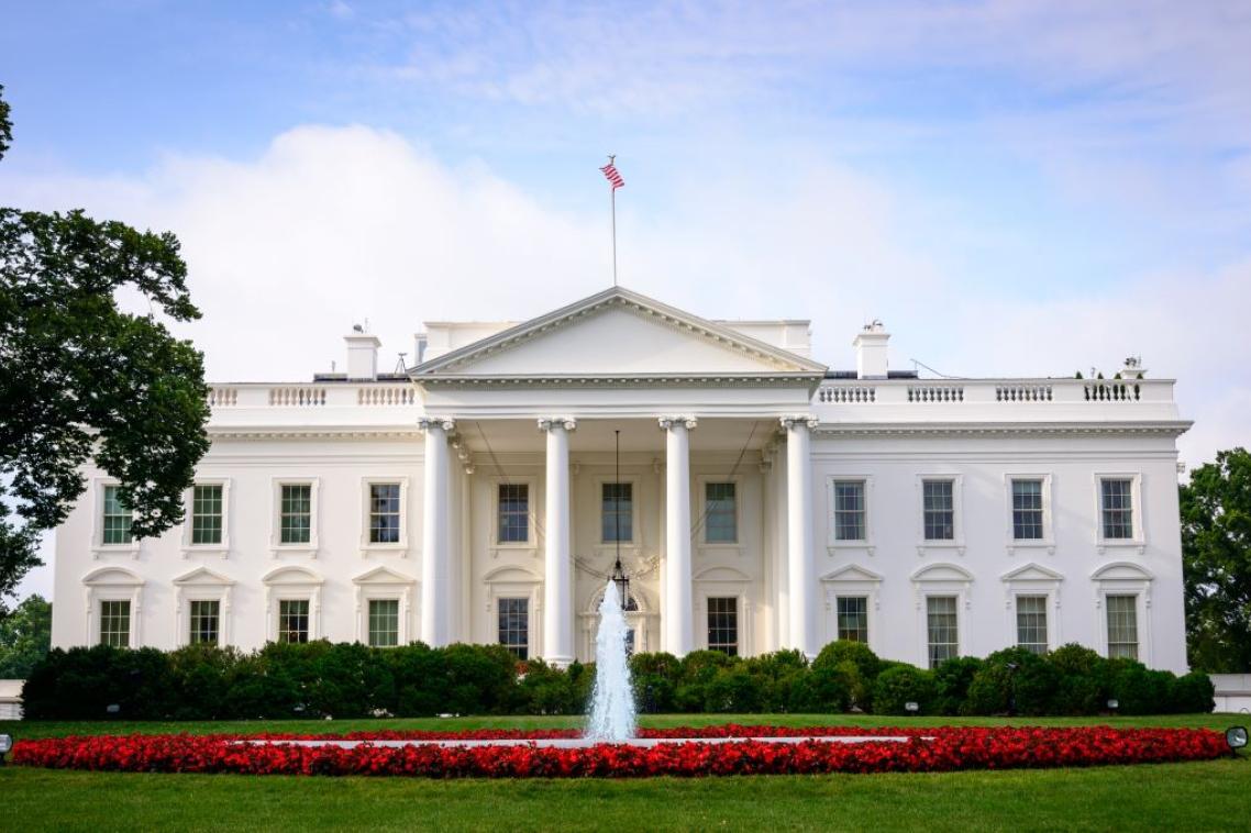 American White house situated behind a lavish garden and fountain